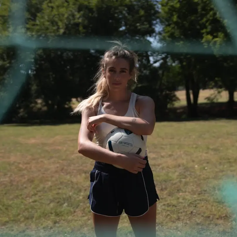 A player holding a Hayworth ball under her arm on a summer field. Photograph by Kate Liddy.